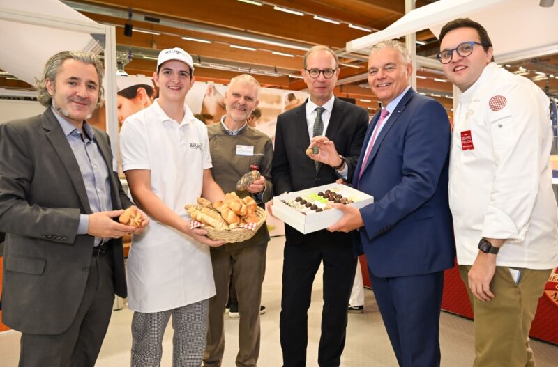 Gruppenfoto bei Messestand, Lehrlinge präsentieren Gebäckstücke