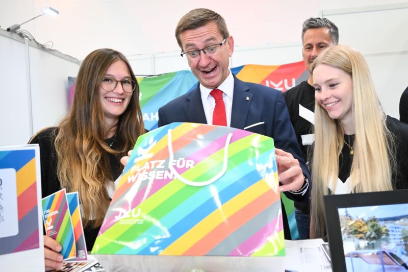 Landesrat Achleitner schaut gespannt in Goodie-Tasche bei einem Messestand