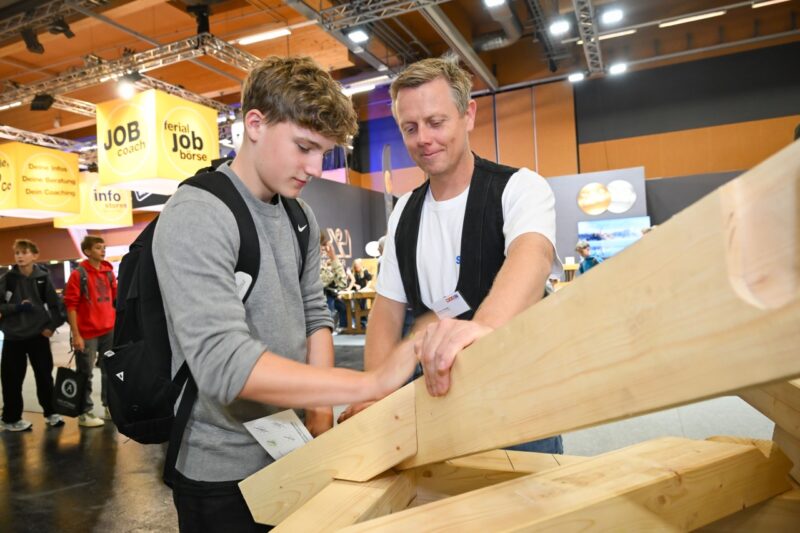 Zwei Personen sägen gemeinsam an einem Holz-Werkstück