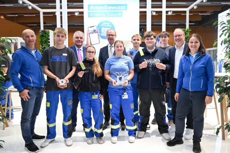 Gruppe junger Fachkräfte in blauer Arbeitskleidung bei Gruppenfoto