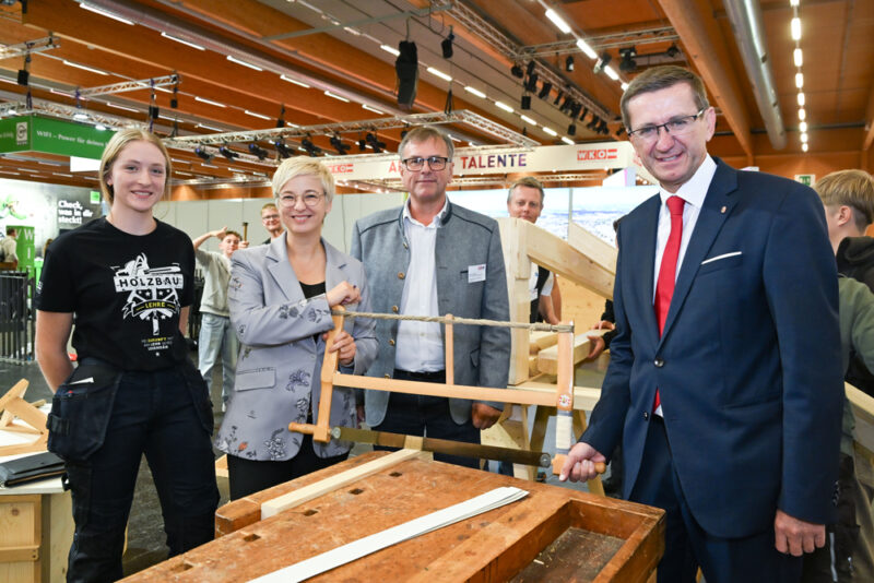 Landesrat Markus Achleitner und WKOÖ-Präsidentin Doris Hummer posen mit Säge beim Messestand für Holzbau