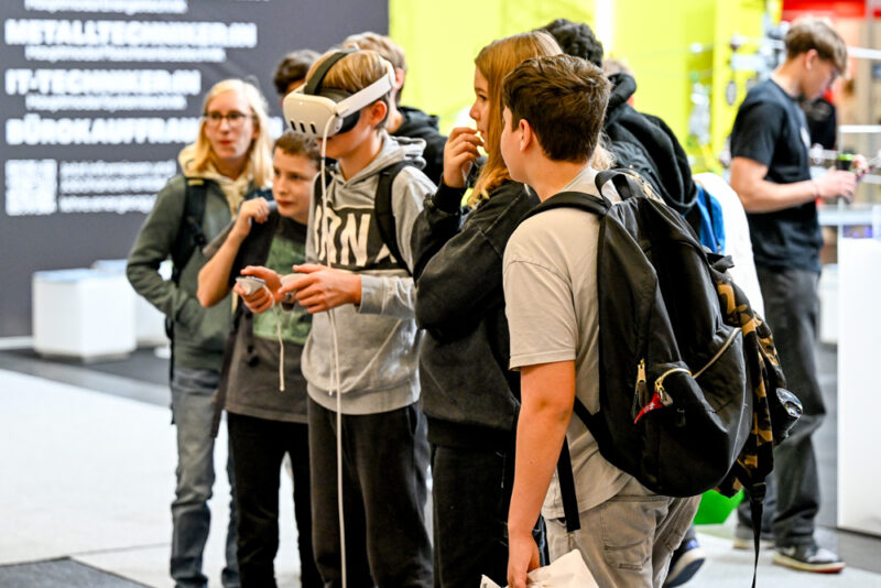 Interessierte Jugendliche testen VR-Brille bei der Messe aus
