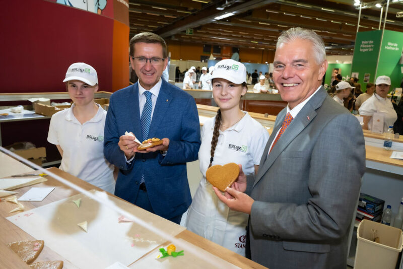 Markus Achleitner und Leo Jindrak verzieren Lebkuchenherz bei Messestand der BS Linz 10