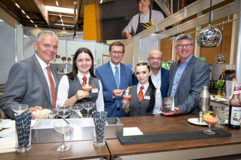 Vertreter der WKO bei Messestand mit Jugendlichen, die Cocktails zubereiten