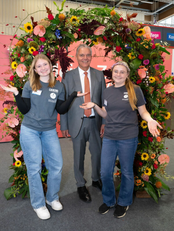 WKO Vertreter mit Jugendlichen vor Blumenkranz