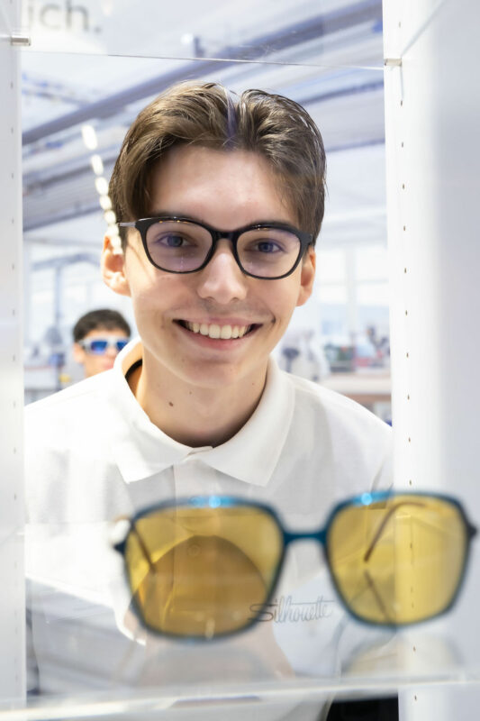 Jugendlicher lacht mit Brille in die Kamera