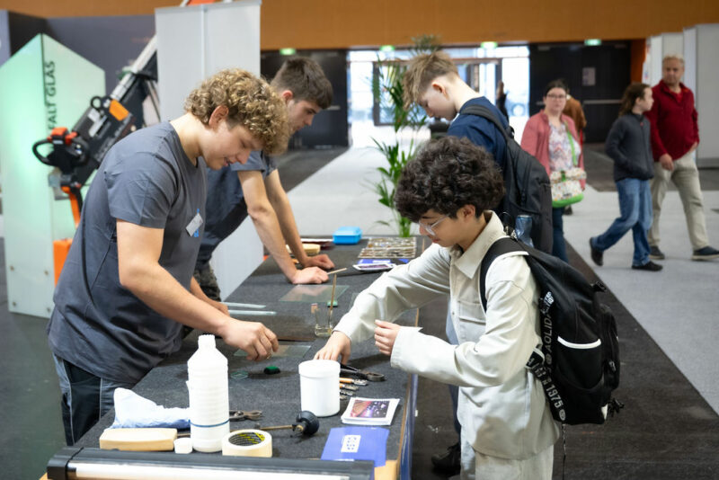 Jugendliche arbeiten konzentriert bei Messestand