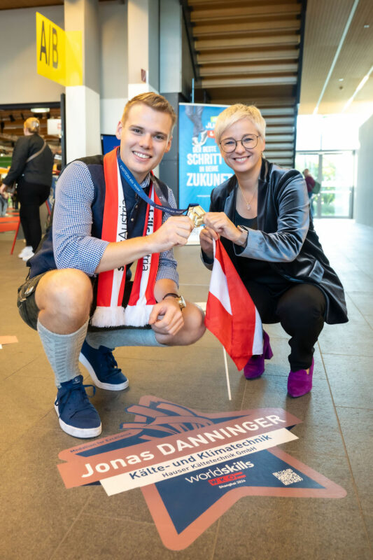 Jonas Danninger und Doris Hummer mit Fahne und Medaille