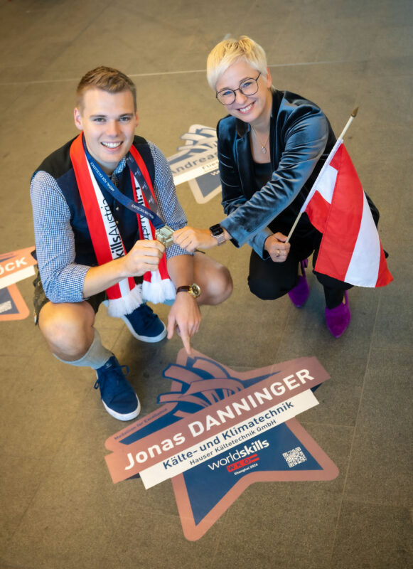 Jonas Danninger und Doris Hummer mit Fahne und Medaille